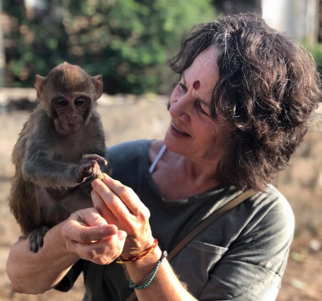 Vegan Storyteller Jeanette McDermott holding a baby monkey while on journalism location in India