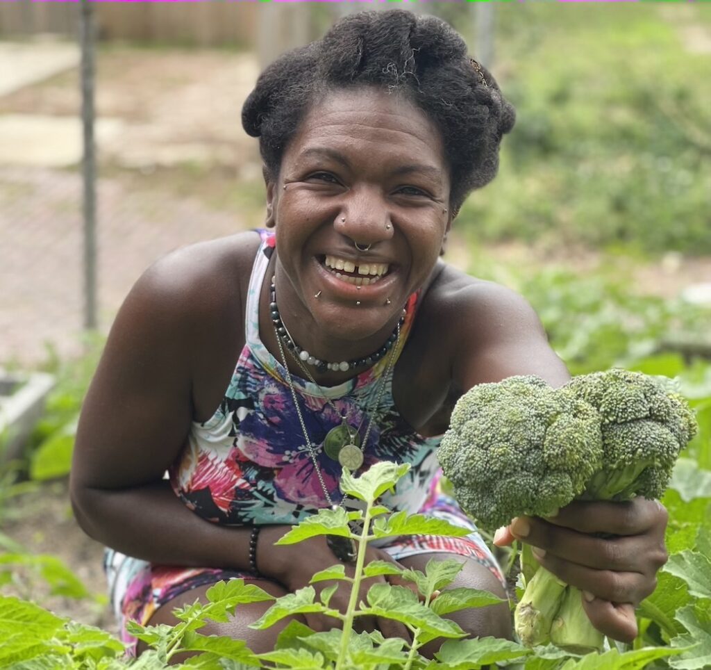Mira Dee picking broccoli from her home garden