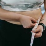 woman measuring her waist with tape measure