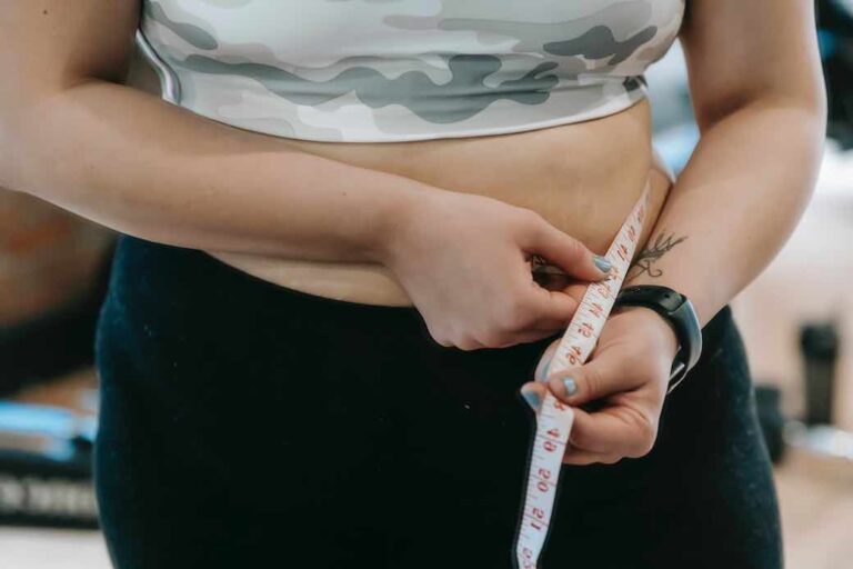 woman measuring her waist with tape measure