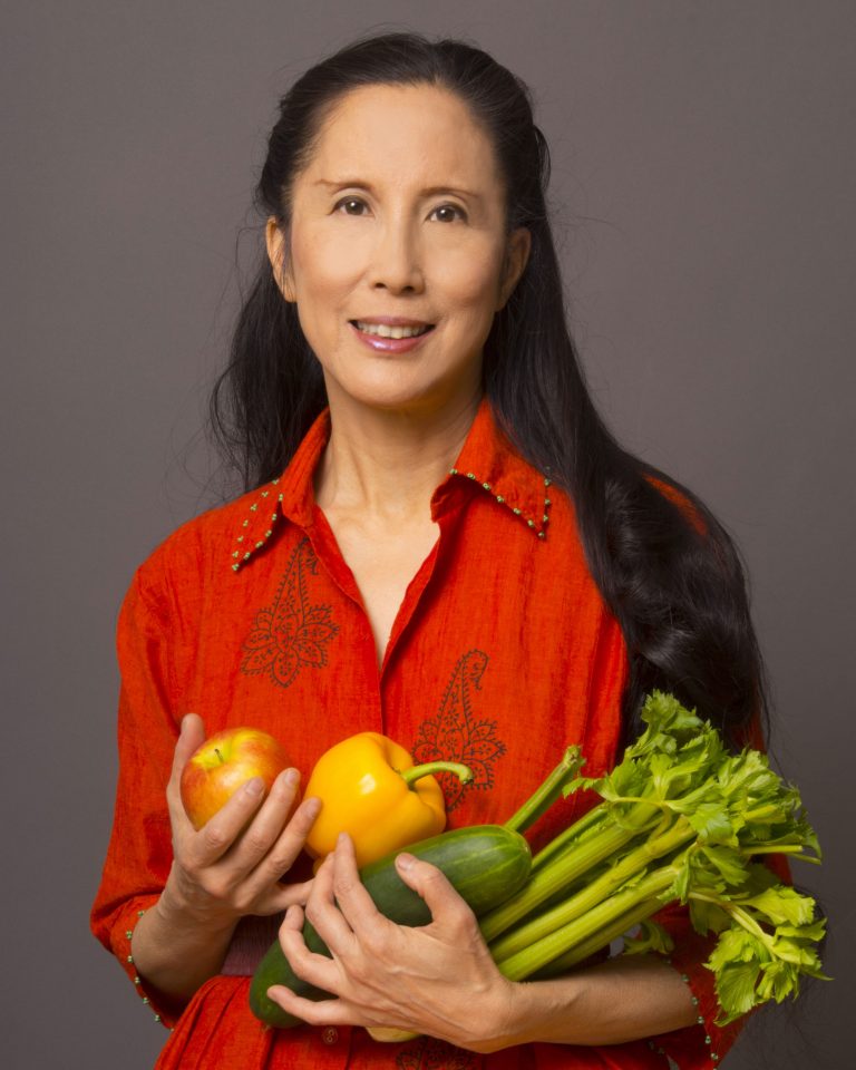Joanne Kong, vegan Renaissance woman carrying armful of vegetables