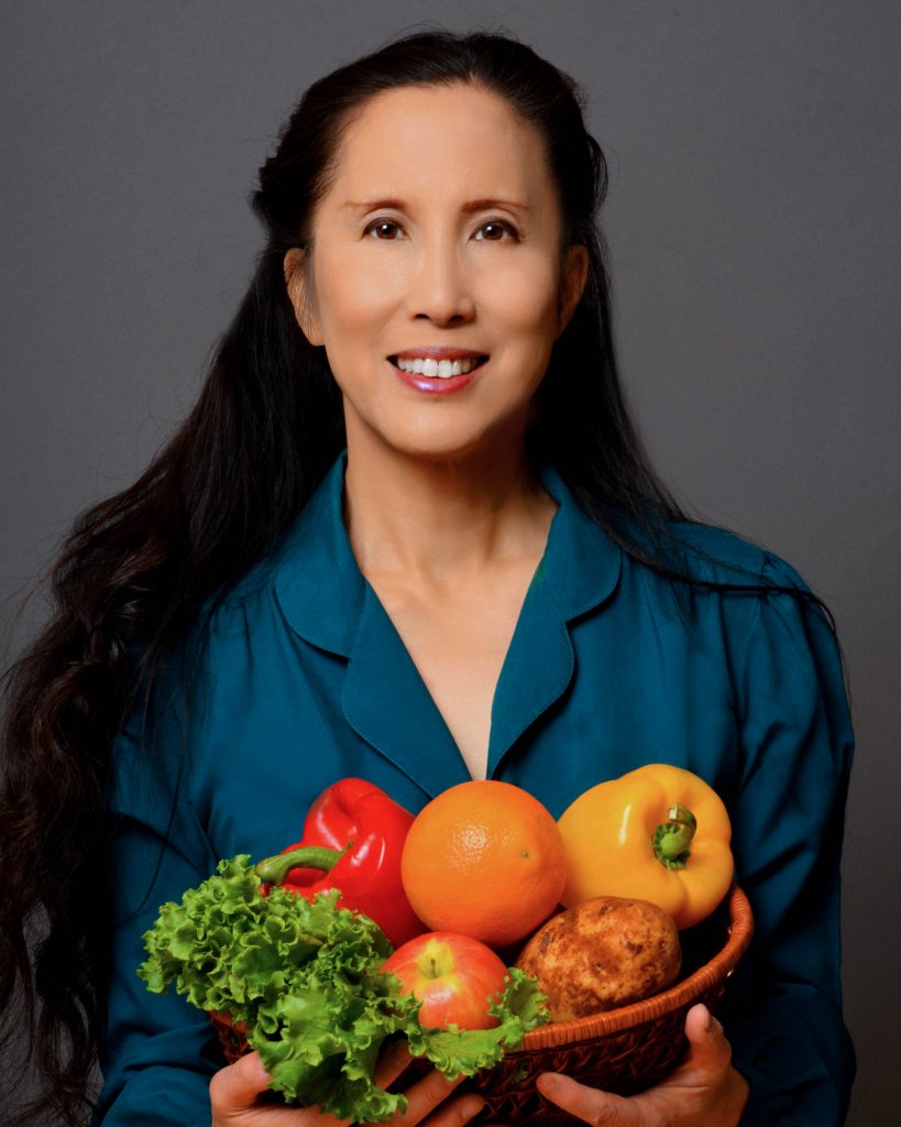 Portrait of Joanne Kong, vegan Renaissance woman, holding armful of vegetables