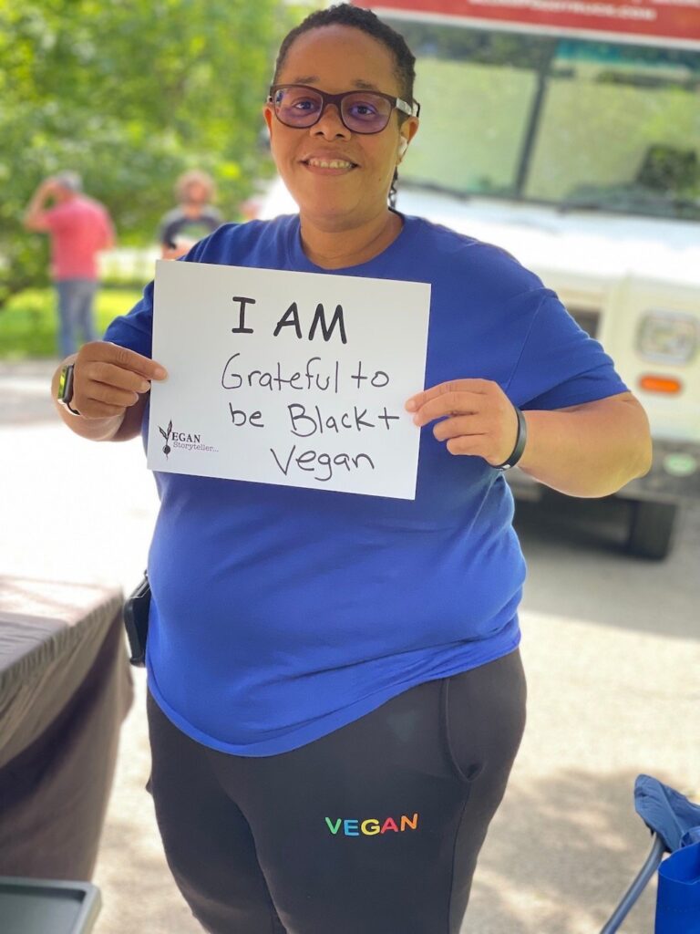 Woman holding a sign that says I am grateful to be Black and vegan